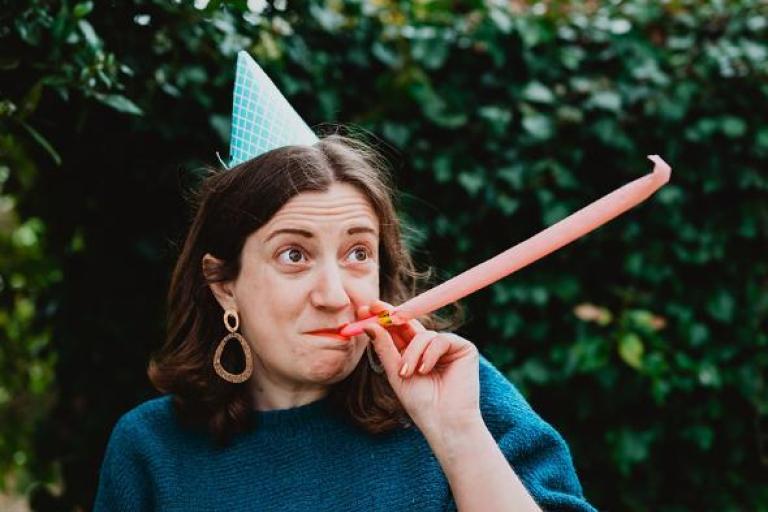 Artist wearing party hat and blowing a party whistle