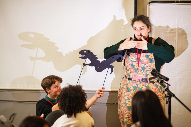 A shadow puppeteer entertaining a small group of children