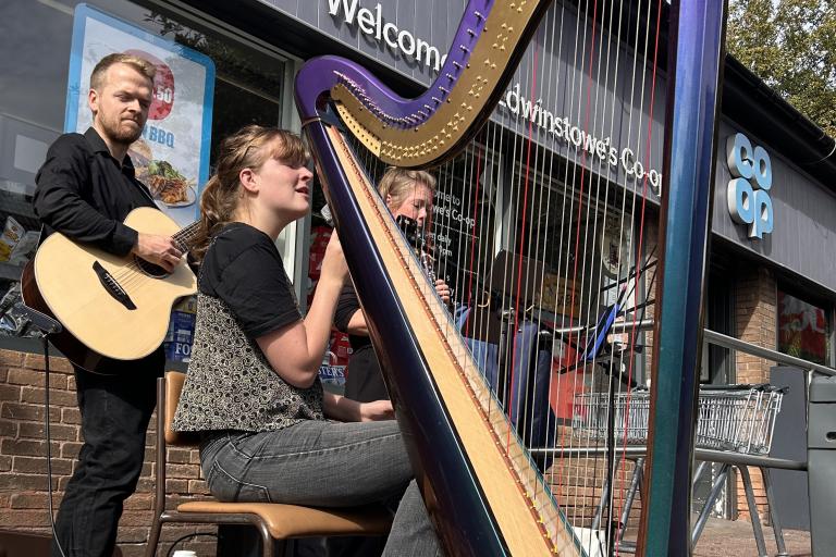 A harpist and guitarist performing outside of a supermarket