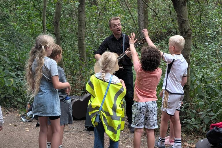 Five children enjoying a walk in the woods whilst their guide plays some music