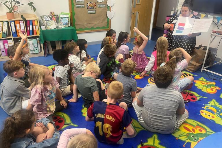Group of achool children seated on the floor listening to a story being read aloud