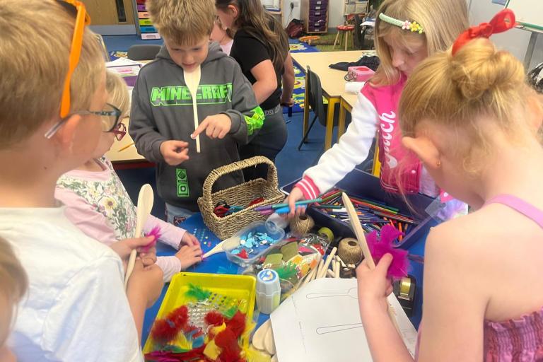 Young children busy decorating wooden spoons to become puppets