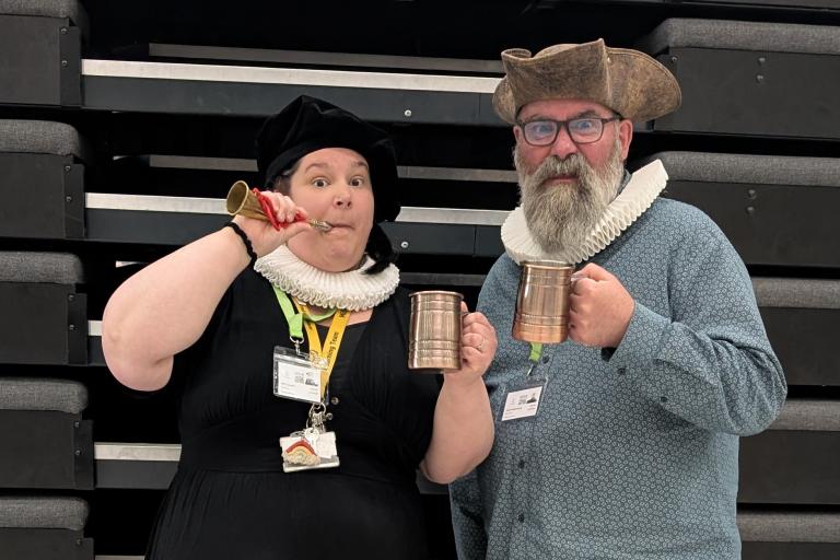 Two actors in period costume raising tankards