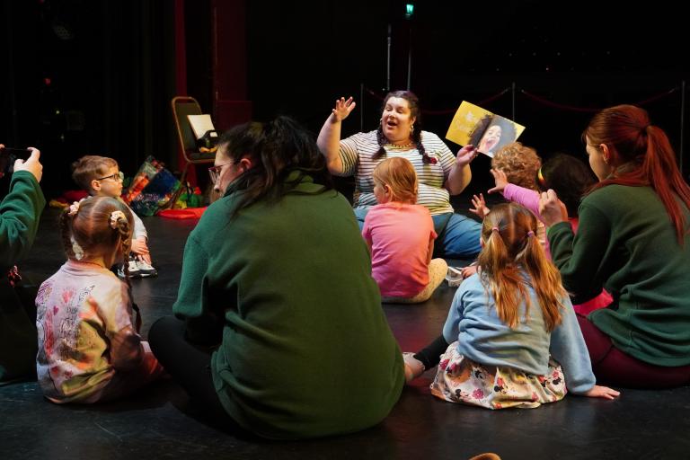 A group of children sitting and listening to a story being read aloud