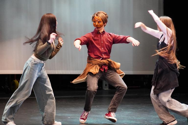 Three children dancing together on stage