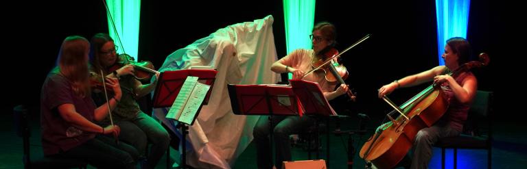 A quartet of musicians playing stringed instruments on stage