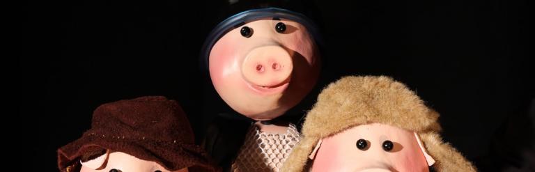 Three pig puppets against a black background