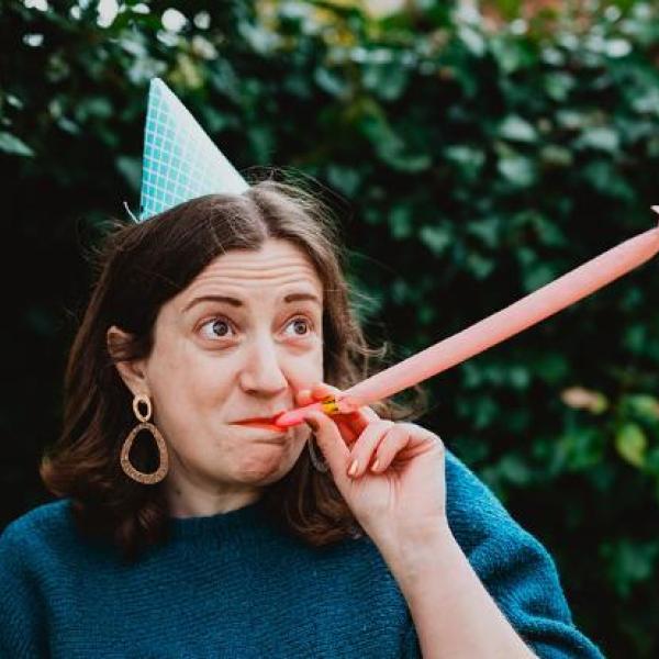Artist wearing party hat and blowing a party whistle